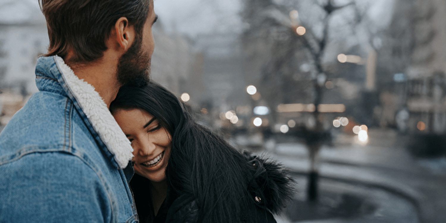 Een man en vrouw staan in de regen en omarmen elkaar, hun liefde zichtbaar ondanks het slechte weer.